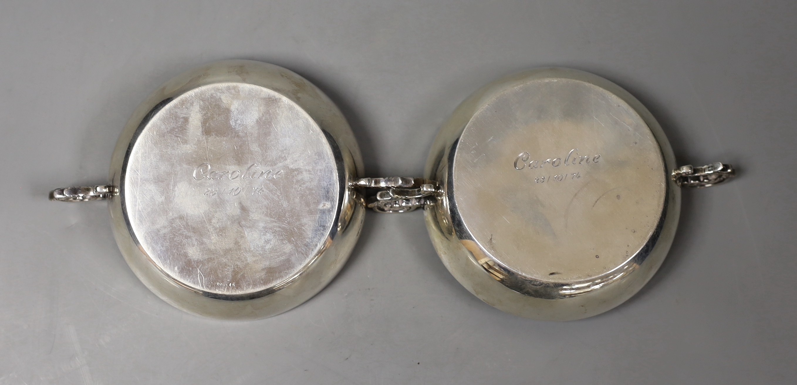 A pair of modern silver two-handled shallow nut dishes, with engraved inscription to the base, Royal Irish Silver Co. Sheffield, 1973, 15.1cm over handles, 193 grams.
